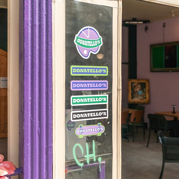 Donatello's restaurant entrance with a purple column and multiple colorful Donatello's stickers on the glass door.