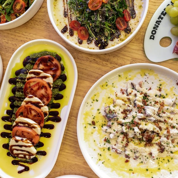 Overhead view of various Italian dishes, including Caprese salad, pasta, and a charcuterie board.