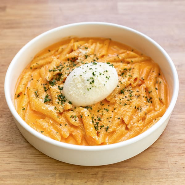Penne pasta in a creamy orange sauce, topped with a dollop of ricotta cheese and parsley.
