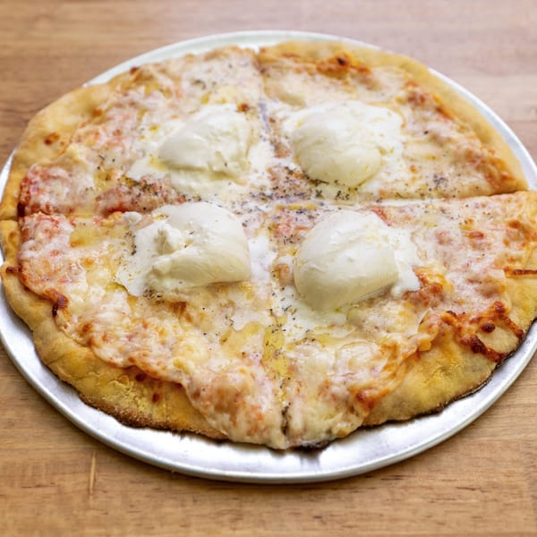 A whole cheese pizza with four dollops of fresh mozzarella and herbs on a metal tray.