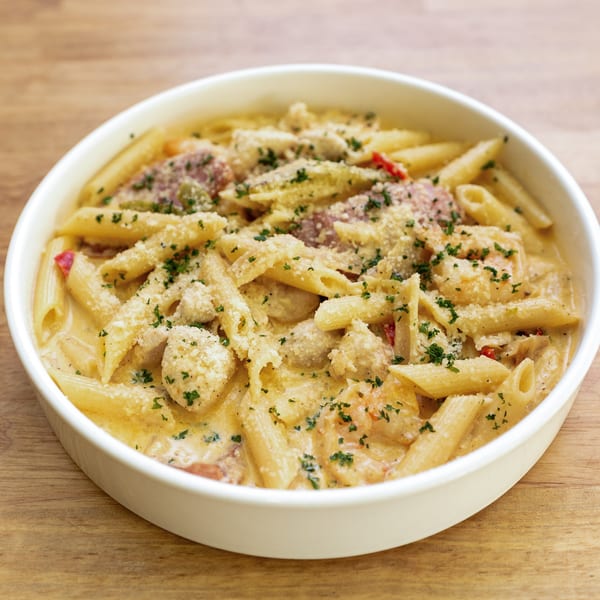 Creamy penne pasta with chicken, shrimp, and vegetables, topped with parmesan and parsley.