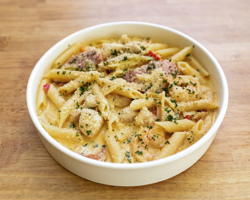 Creamy penne pasta with chicken, shrimp, and vegetables, topped with parmesan and parsley.